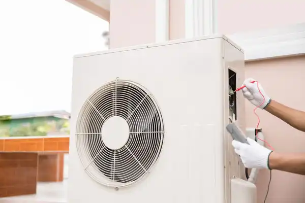 Technician in gloves using tools to check an outdoor air conditioning unit.