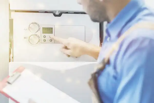 A person in a blue shirt adjusts the settings on a digital control panel, with a clipboard in the other hand.